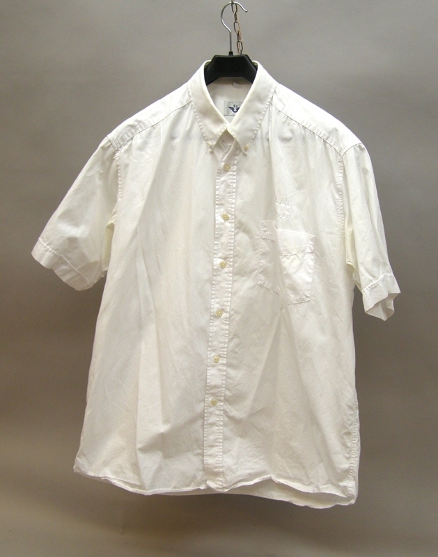 Vit kortärmad bomullsskjorta med krage. Varsin plastknapp på vardera kragsnibb. En bröstficka. Sju stycken vita plastknappar. På insidan skjortan en vit lapp med SJ:s logotyp i mörkblått. Storlek: XL 44-45.