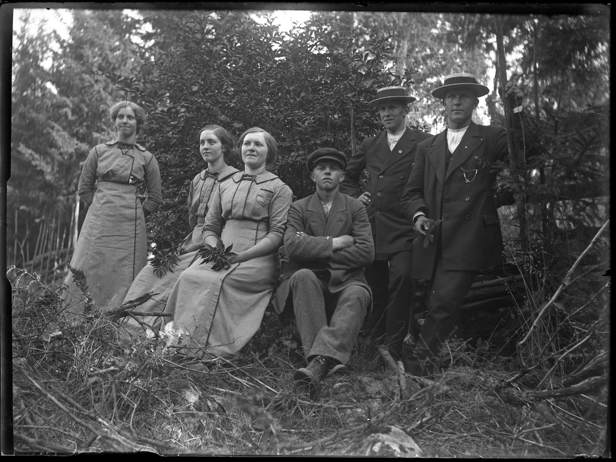 Tre damer och tre män i skogsbacke.