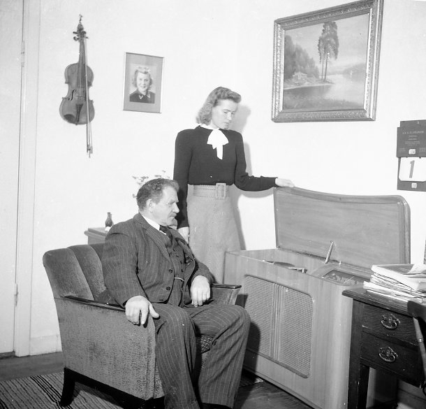 Man (äldre) och kvinna som beskådar en radiogrammofon.
