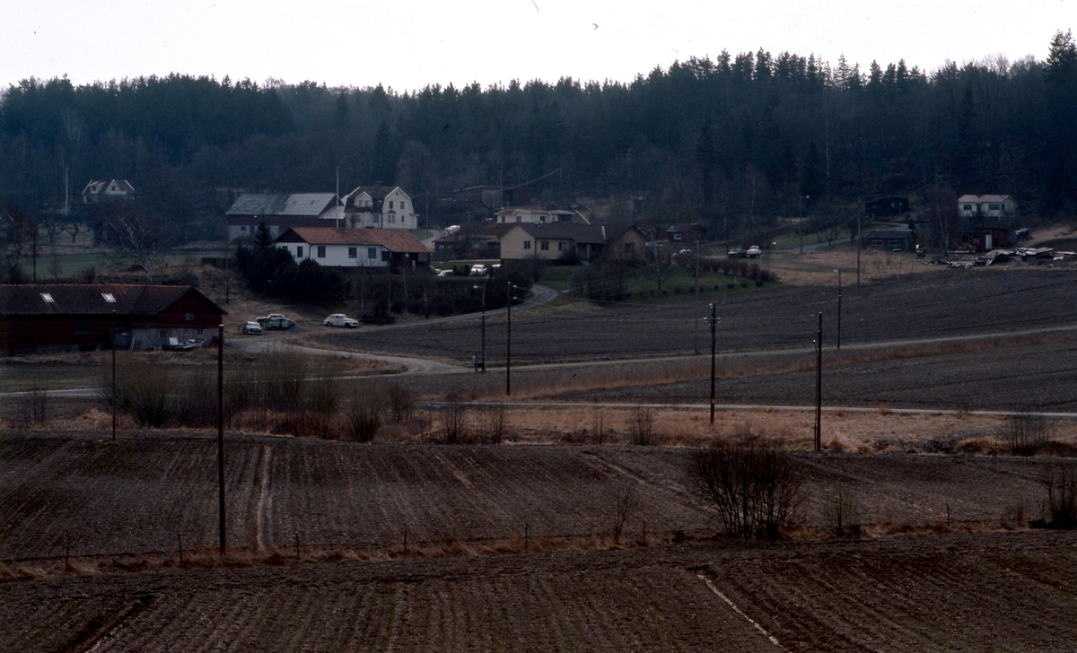 Vy över odlingsmark och Heljered Mellan- och Sörgårdar år 1978. Sandsjöbacka naturreservat ses i bakgrunden.