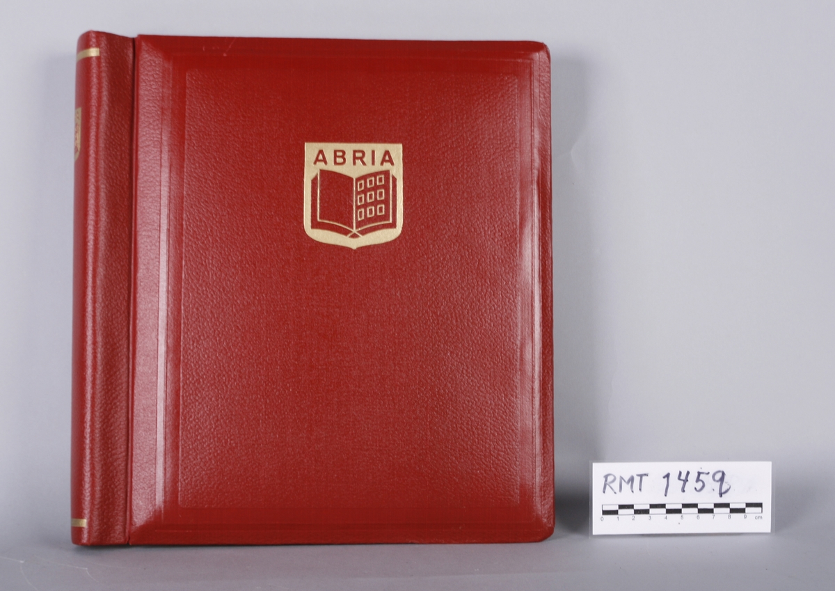 Frimerkealbum i rød innbinding. Gravert inn merke på albumet i gullfarge. Merket "ABRIA" og under dette logo med et frimerkealbum. Innsiden på permen har samme logo, både første og siste side i albumet.