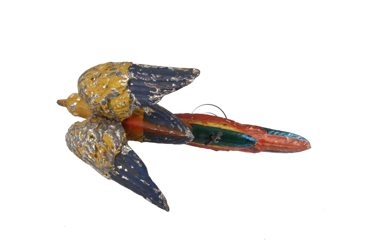 Mekanisk leketøy som kan trekkes opp slik at papegøyens vinger beveger seg.