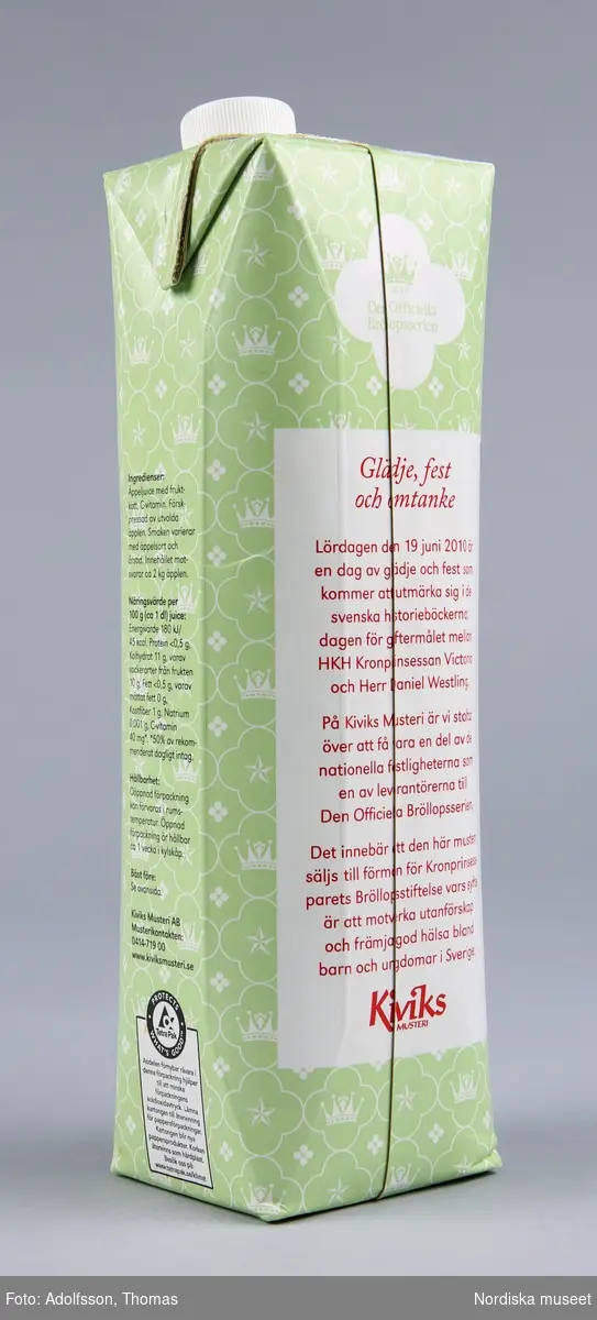 a) Tetra Pak, åttkantig förpackning för 1l äppelmust från Kviks musteri. Förpackningen bär "den officiella bröllopsseriens" logotyp samt mönster med stiliserad krona och stjärna. På framsidan ett foto av äpplen på gren. Förpackningen öppnas med en b) skruvkork av plast. 
Text på förpackningen: 
"2010 Den Officiella Bröllopsserien",
"Årets skörd ÄPPELMUST Utvalda och handplockade äpplen från Österlen",
"Säljes till förmån för Kronprinsessparets Bröllopsstiftelse vars syfte är att motverka utanförskap och främja god hälsa bland barn  och ungdomar i Sverige.", 
"MED FRUKTKÖTT", "1L","Kiviks MUSTERI", baksida:"2010 Den Officiella Bröllopsserien", 
"Glädje, fest och omtanke", "Lördagen den 19 juni 2010 är en dag av glädje och fest som kommer att utmärka sig i historieböckerna; dagen för giftemålet mellan HKH Kronprinsessan Victoria och Herr Daniel Westling. På Kiviks Musteri är vi stolta över att få vara en del av de nationella festligheterna som en av leverantörerna till Den Officiella Bröllopsserien. Det innebär att den här musten säljs till förmån för Kronprinsessparets Bröllopsstiftelse var syfte är att motverka utanförskap och främja hälsa bland barn och ungdomar i Sverige."
,"Kiviks MUSTERI", 
sida: "Ingredienser:" utdrag: "Färskpressade utvalda äpplen.", "Näringsvärde per 100g (ca 1dl) juice:", utdrag: "C-vitamin 40 mg*.*50% av rekommenderat dagligt intag.", "Hållbarhet:Oöppnad förpackning kan förvaras i rumstemperatur. Öppnad förpackning är hållbar ca 1 vecka i kylskåp", 
"Bäst före: Se ovansida", "Kiviks Musteri AB Musterikontakten: 041471900 www.kiviksmusteri.se", "Protects what's good Tetra Pak" samt text om hur förpackningen ska återvinnas och förpackningens "koldioxidavtryck". 
Sida: "FRÅN HJÄRTAT AV ÖSTERLEN"  efter rubriken följer en text om hur musten är tillverkad enligt tradition på samma sätt som farfar gjorde. 9 olika äppelsorter används till musten som provsmakas av "erfarna äppelmakare". 1888 startades musteriet och samma familj driver det idag. "Familjens passion för traditioner,lokala råvaror och äkta livskvalitét är ledstjärnor än idag", 
topp: "Bäst före: 22-11 2010 16:44 0144".
/Johanna Krumlinde 2012