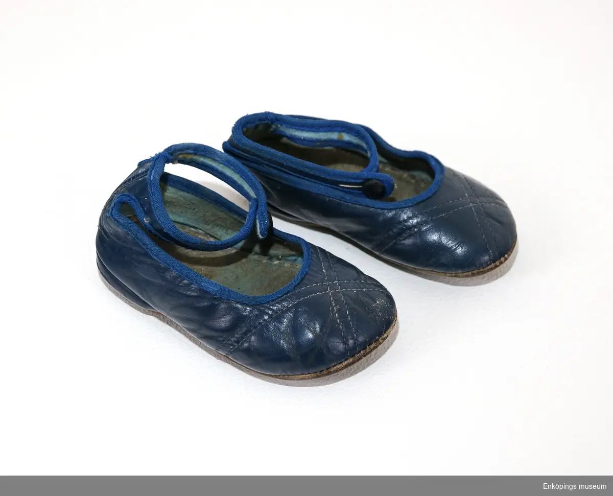 Blå barnsko med slejf, sandalmodell. Skorna är från 1950-talet.