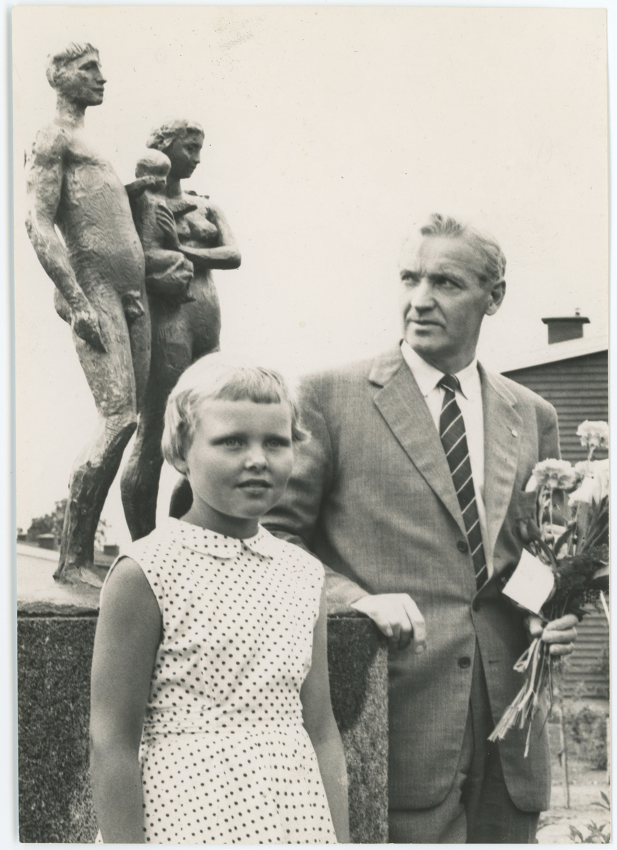 Olav Selvaag og blomsterpike foran skulpturen "Ung familie" av Per Ung, gave fra Olav Selvaag ved barnehagen på Tronvik. To kopier av samme bilde.