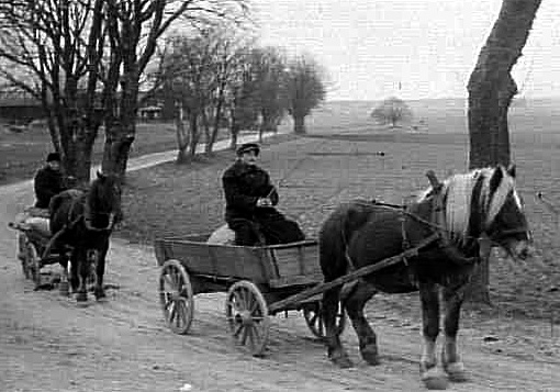 Två hästekipage passerar Prästgården i Fredsberg, sannolikt på väg till kvarnen då säckar skymtas på vagnarna.