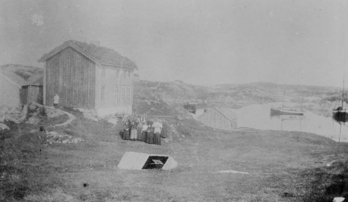Bildet viser en gruppe mennesker avbildet foran et hus. Lillekjerringvåg, Dolmøy, Hitra, 1912 - 1922.