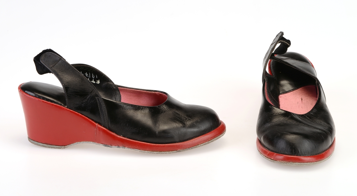 Et par dametøfler av skinn/lær med kilehæl. Overdelen av skoen er av svart lær, mens kilehælen og den nedre delen av skoen er av rødt lær. De er foret med rosa silkefor. På hælen er det svart skinn. Skoene har hælstropper av svart fløyel. Stroppene er elastiske. Yttersålen er av grå semsket lær.