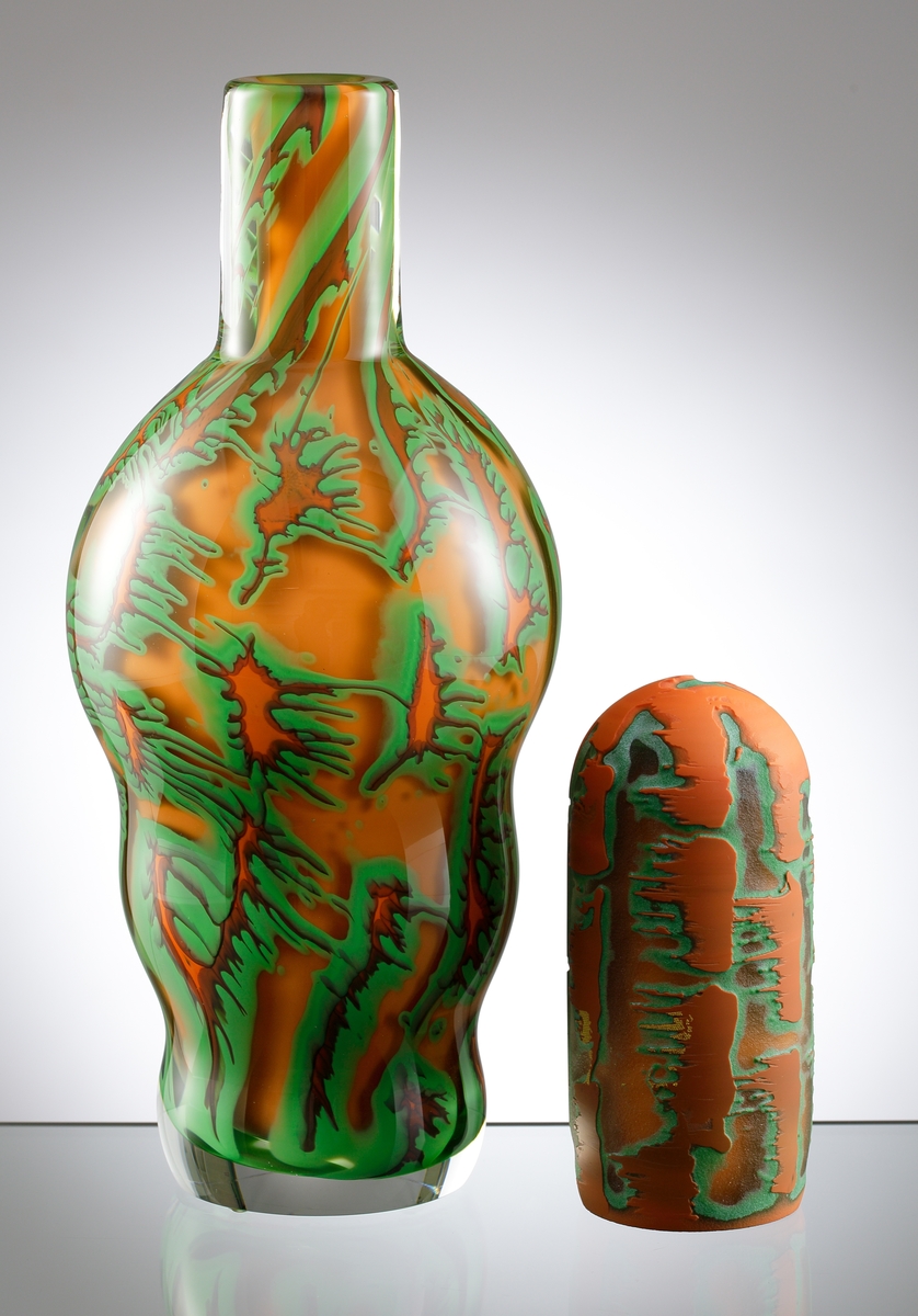 Dubbel-graal av Helen Krantz, i form av en kalebassformad vas med oregelbundet mönster i grönt och orange. Dubbel-graal innebär att det är mönster i dubbla lager. Konstnären och formgivaren är Helen Krantz.