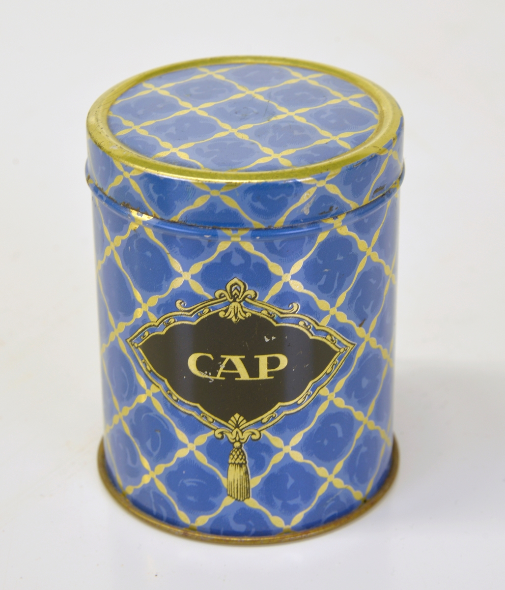 Lackerad i blått/guld med texten: CAP mot svart
botten.
