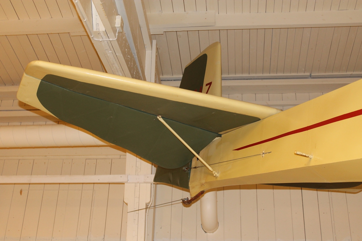 Segelflygplan av modell Grunau Baby. Ensitsigt segelflygplan, helt tillverkat i trä, dukspänd. Målad vit med röd blixt och grå typbeteckning.