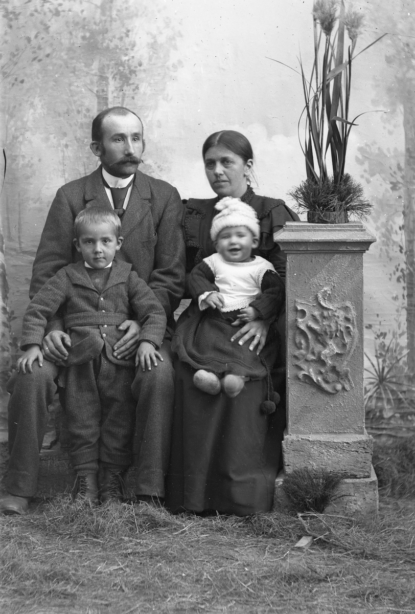Familieportrett av to voksne og to barn. Foran fra venstre: John H. Kveen (1894-1955) og Vebjørn Kveen (1897-1918). Bak: Halvor Kveen (1864-1950) og Minde Kveen f. Strandvold (1864-1936).