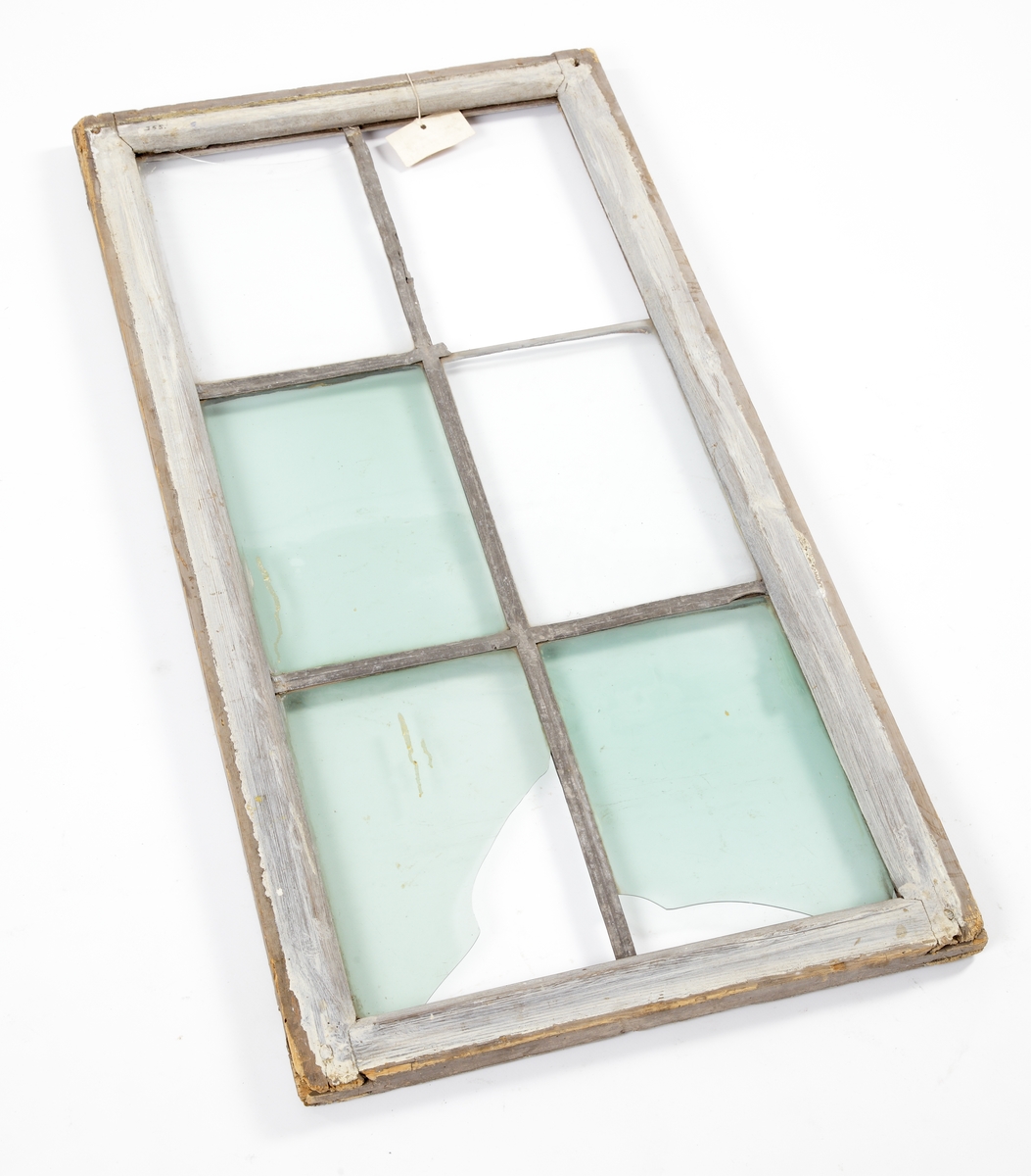 Fönsterram av trä, målad i vitt/ljusblått. Blyspröjsar. Sex glasrutor med grönt glas i olika nyanser.