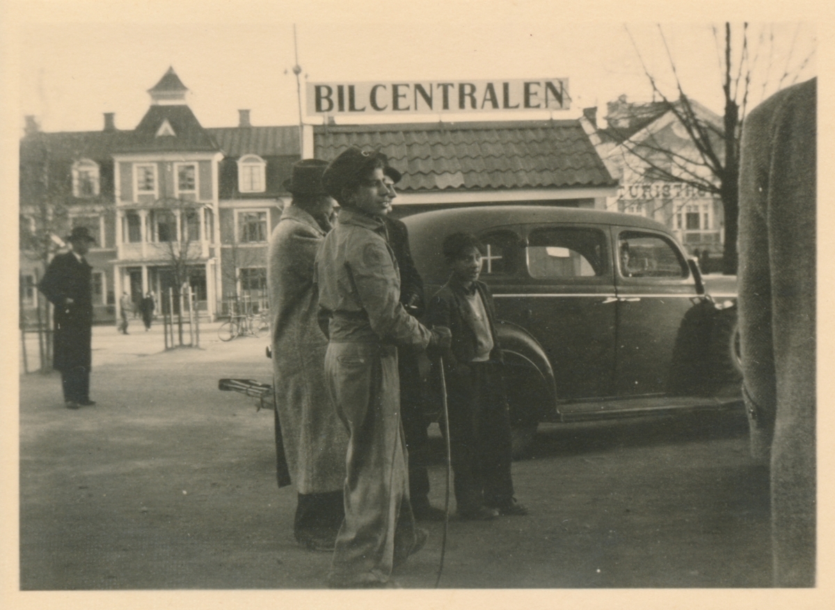 En samling unga män och pojkar står framför en bil. Bilden är troligen tagen i samband med marknaden i Torsby.