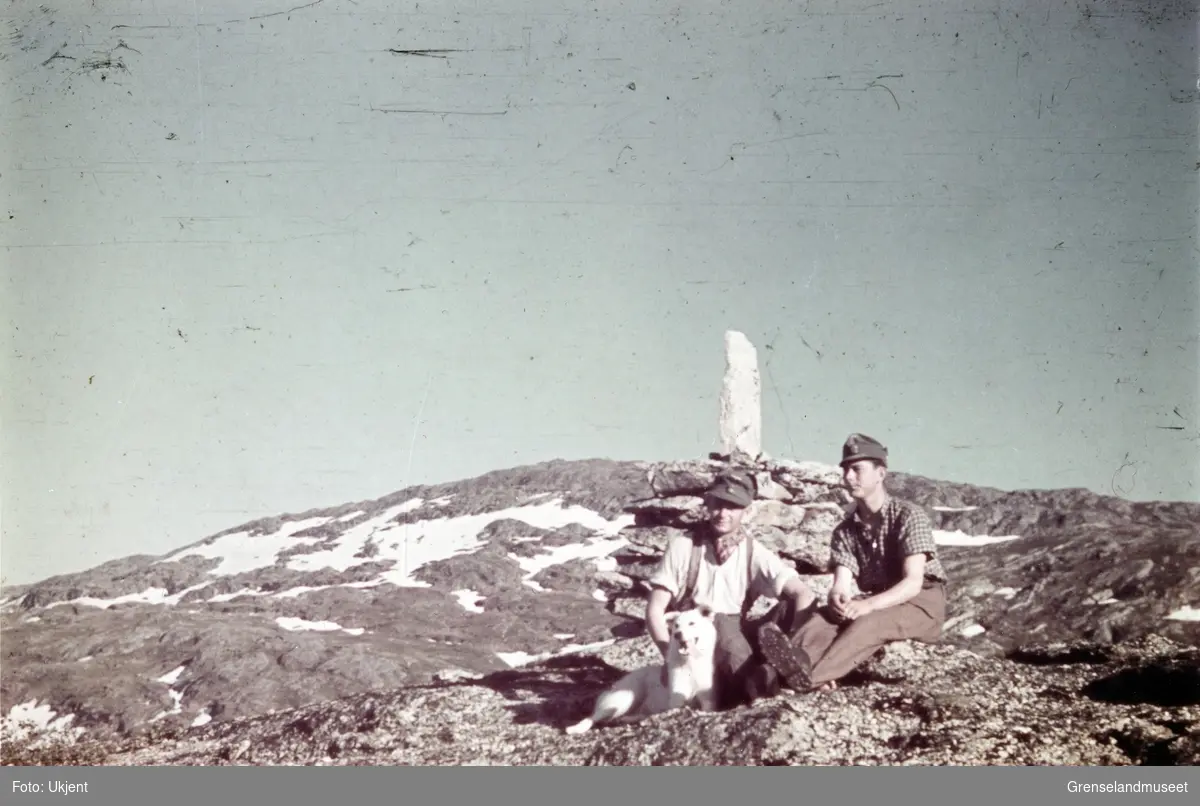 To soldater og en hund sitter foran en varde i et fjellandskap. Grensen mellom Finland og Sovjet?