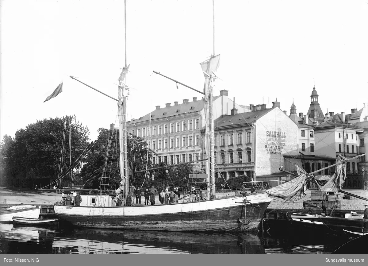 Segelskuta vid Fisktorget. På Selångersån kunde segelfartygen komma ända upp mot Storbron p g a att Tivolibron var svängbar. Holmströmska huset i bakgrunden med saluhall och fiskhallen som låg närmast Sjögatan. Längs till höger skymtar Näslund & Wiklunds järnhandel.