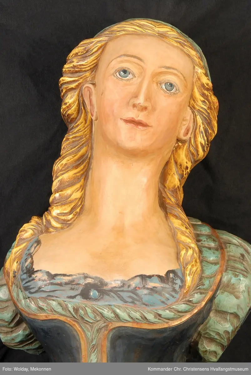 Kvinnefigur med gyllent hår, blå kjole.