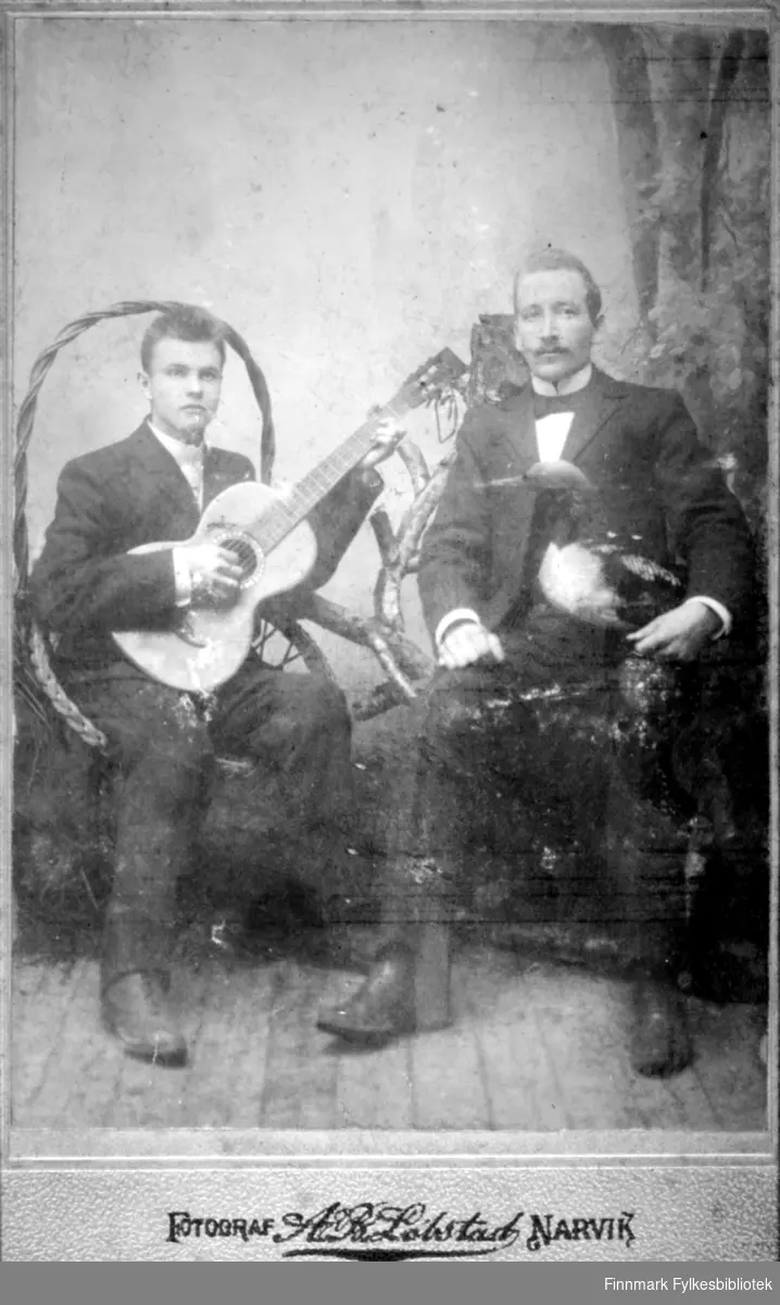 Visittkort. To menn, han andre har gitar i hendene. Fotograf A B Lobstast (?) Narvik.