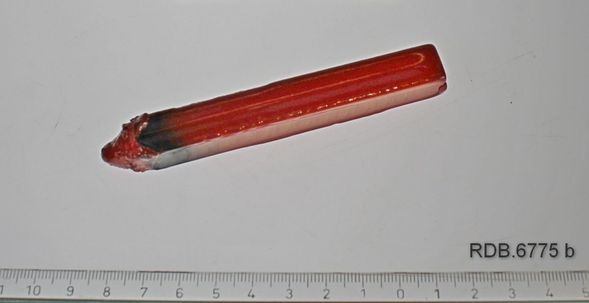 Rektangulær blyantformet rød lakkstang, spiss i en ende etter å ha vært brukt.