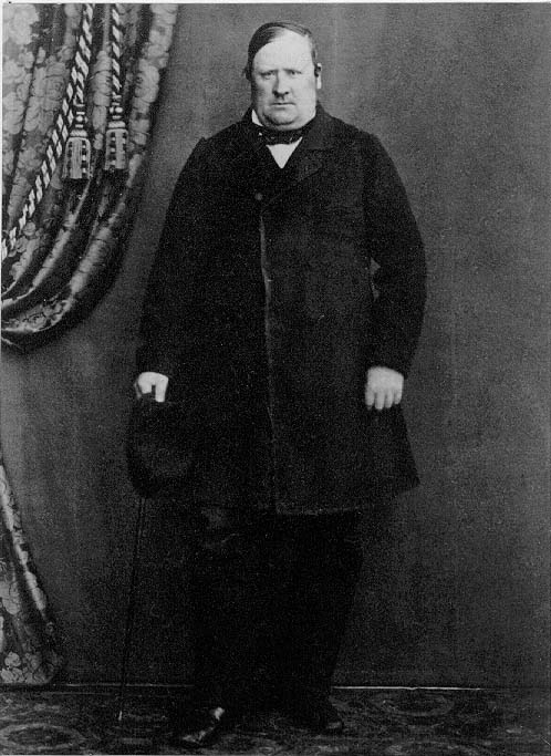 Porträtt av rådman Sven Johan Petersson i Gränna, i helfigur. Han står med en hatt och käpp i höger hand.