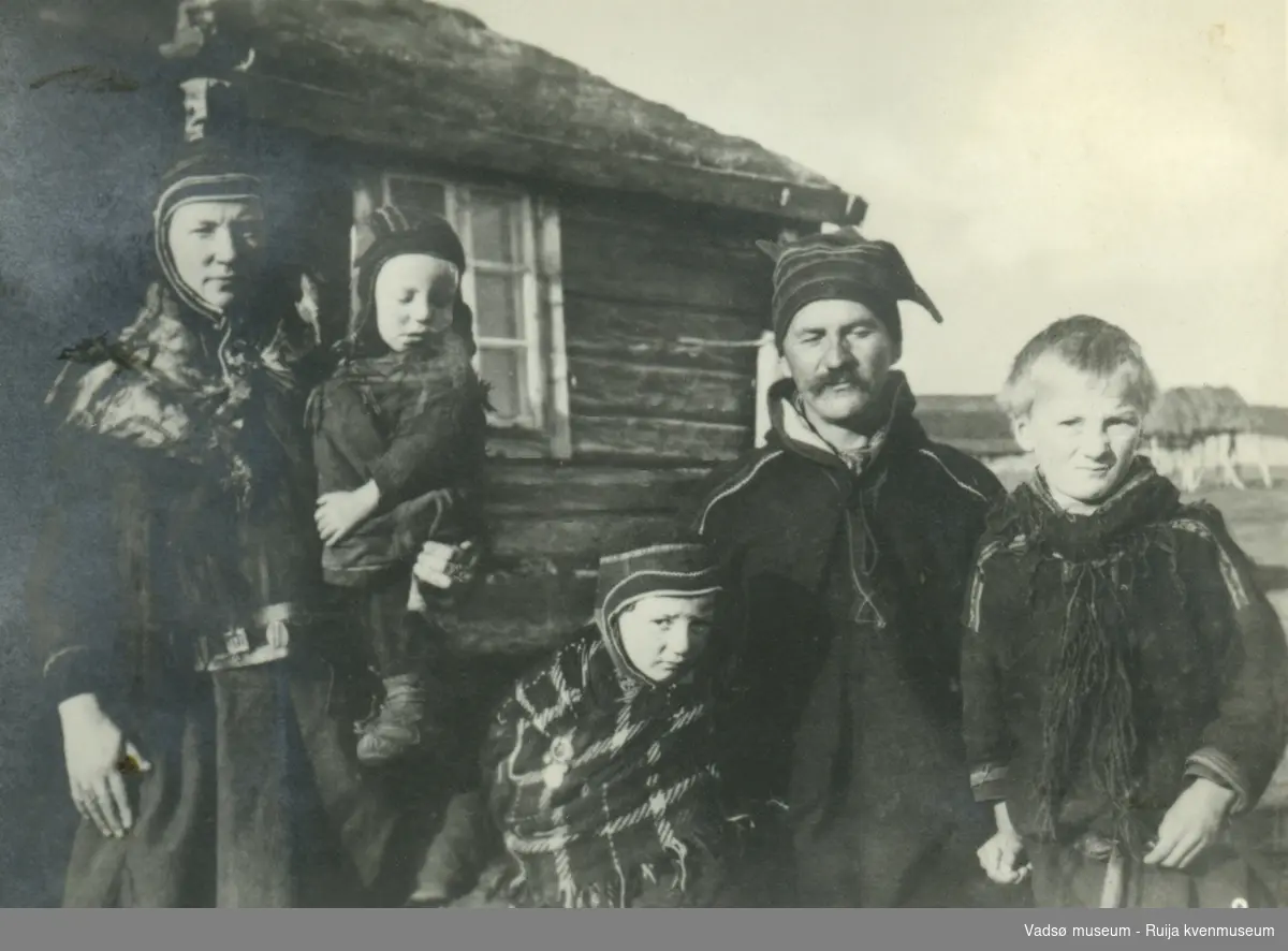 Ukjent samisk familie avbildet foran trehus med torv på taket. Nummerert med nummer 8.