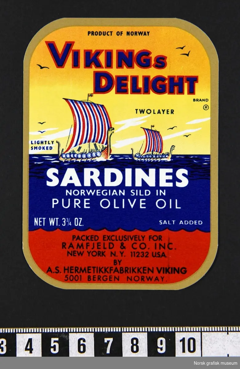 Etikett i gult, blått og rødt, opmkranset av ramme i gull og med fremstilling av to vikingskip på havet. 

"Sardines Norwegian sild in pure olive oil"