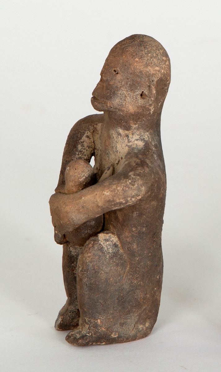 Figurin i leirgods, fremstiller en stilisert menneskeskikkelse med barn i armene, muligens ammende.