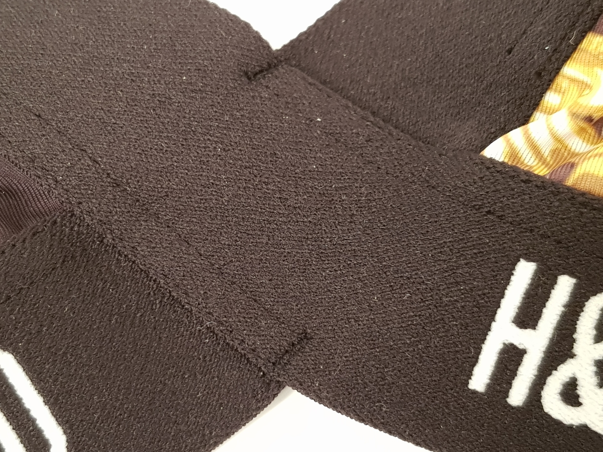 BH eller solliv av ganske blankt materiale, med påtrykt mønster i form av tettstilte, gullfargede lenker og hengelåser mot en bakgrunn med dyremønster. Nedre og øvre linning er svart med gjentagende "H&Moschino" i hvitt.