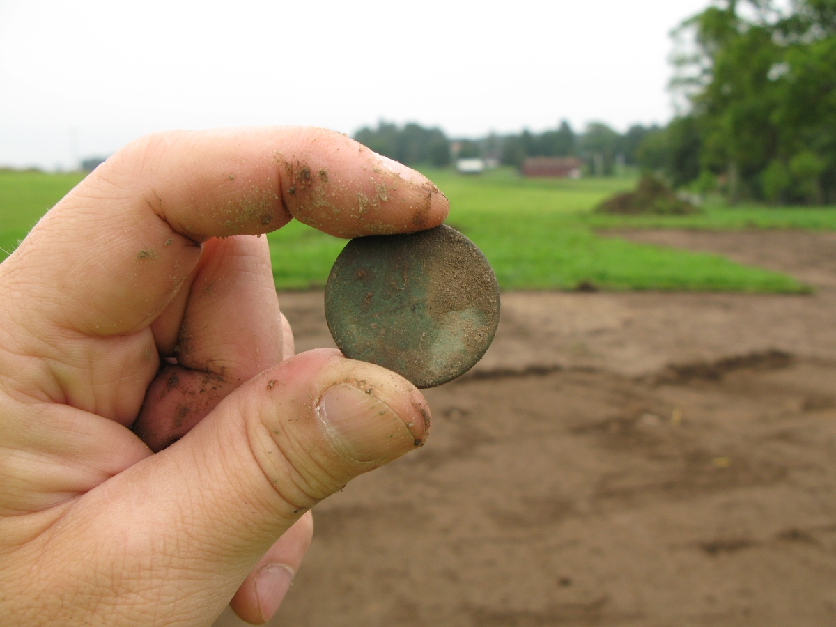Ett nyupptaget mynt från 1700-talet. Metalldetekteringsfynd gjort vid en arkeologisk undersökning i Odensjö i Barnarp socken i Jönköpings kommun.