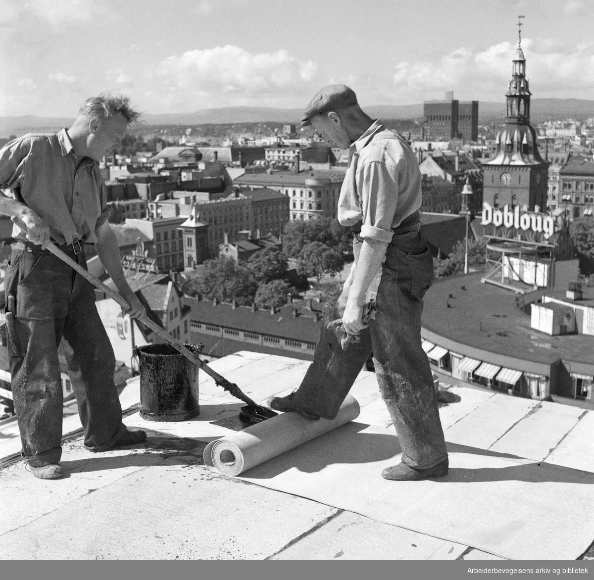 Taktekkere i arbeid på det kommende Hotel Viking. Her omtalt som Folkehotellet. I dag Clarion Hotel, The Hub. Oslo Rådhus, Oslo Domkirke og Doblouggården i bakgrunnen. August 1950.