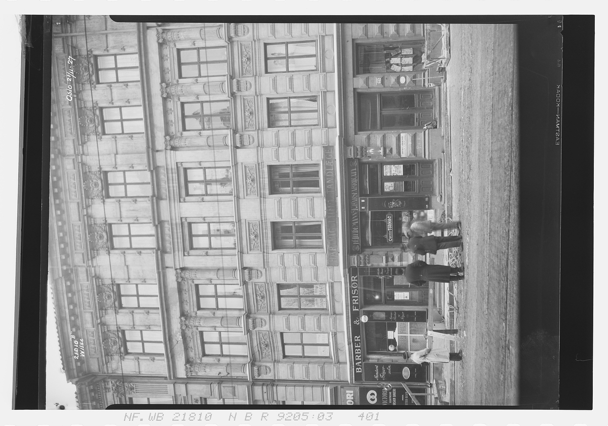 Bygård i Bogstadveien 25 med butikker i 1. etasje. Murmester Gundersen jobber på fasaden. Fotografert 1927.