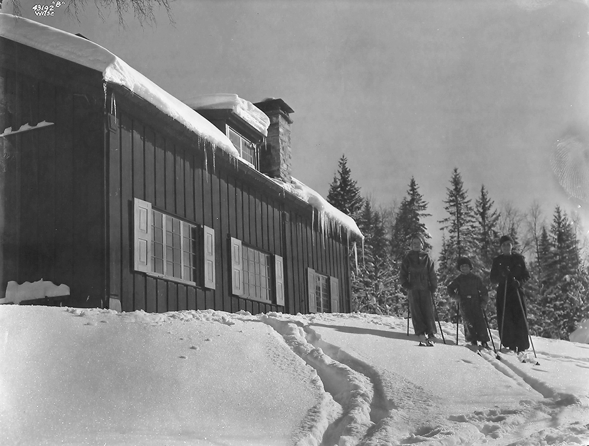 Barn står på ski utenfor et stort hus.