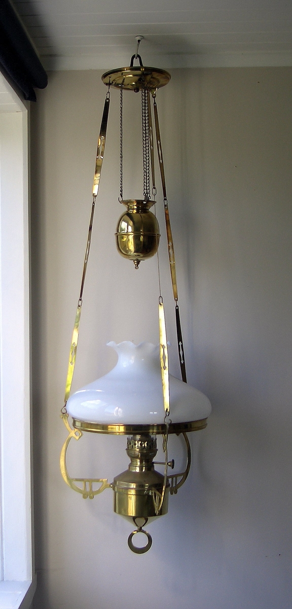 Taklampe for parafin. Lampa har ein sylindrisk haldar i botn. På undersida er haldaren kjegleforma med ein rund ring i spissen. Frå haldaren går tre armar opp mot eit sirkelrundt stativ for lampeskjerm i kvitt glas. Skjermen har runda korpus som smalnar inn mot toppen og deretter vidast ut igjen heilt øvst. I haldaren ein laus parafinbrennar med  stillskrue for veike. Lampeglas festast i haldar på toppen av parafinbrennaren og stikk opp gjennom opninga i lampeskjermen. Lampeglaset er sylindrisk med innsnevring omlag 1/3 opp på glaset. Lampa heng i tre lenker er festa til kvar av armane og går opp til eit skålforma takfeste øvst på lampa. Lenkene har kjettingar i øvre ende som går over trinser i takfestet og ned til eit lampelodd som heng under takfestet. Høgda på lampa regulerast ved å heve eller senke loddet.