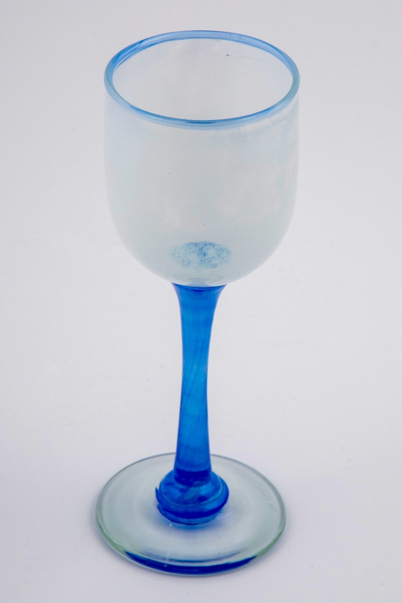 Vinglass med hvit halvgjennomskinnelig kupa. Munningen er markert med blålig glass. Stetten er utført i klart blåfarget glass, og hviler på en sirkulær fot.