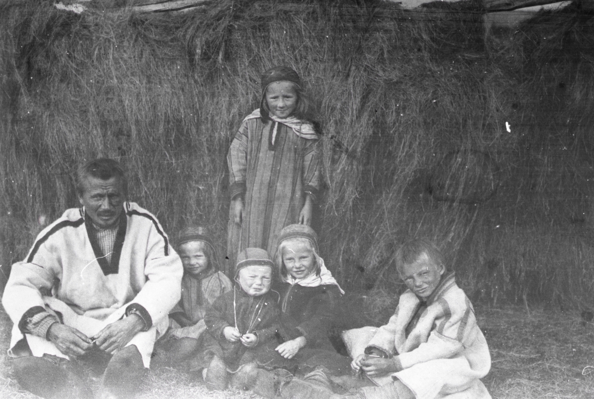 Gruppeportrett av en mann og fem barn i tradisjonelle drakter. Fra venstre; Mathis Klemetsen og barna hans; Gunhild, Anna Maria, Elen og Mathis. Stående bak er Marit Sofie Nilsdatter Biti.