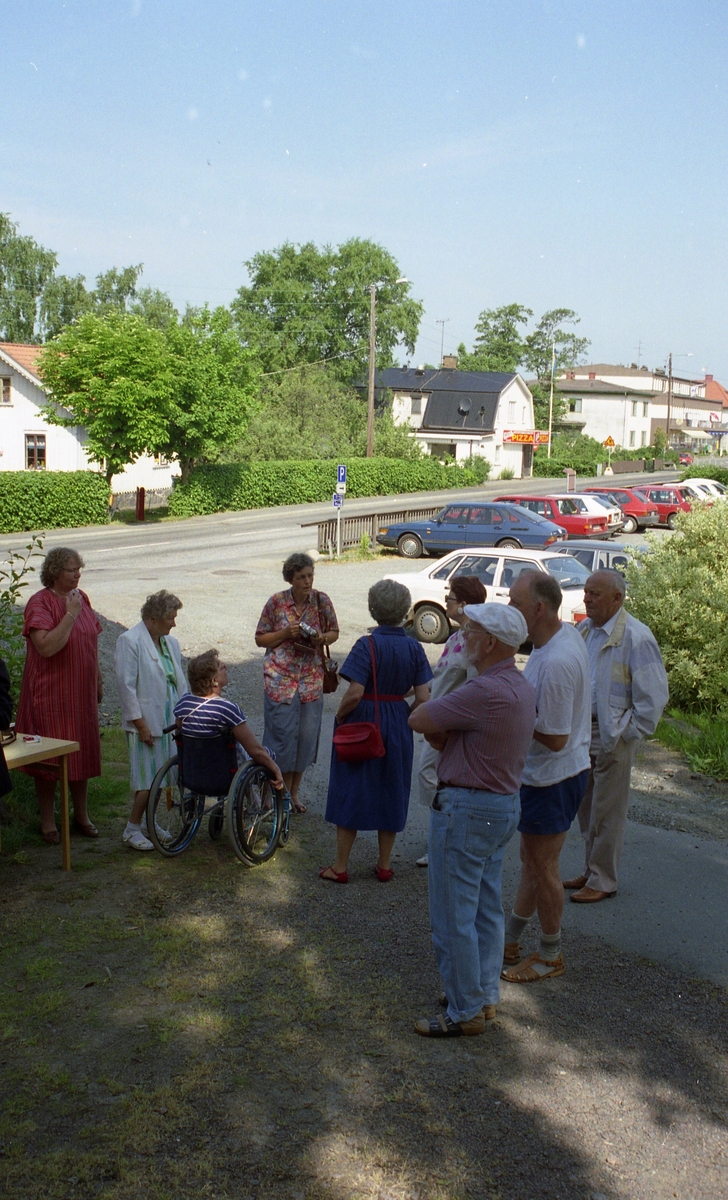 Invigning av Ekebackens Hantverksgård (tidigare John Lindströms möbelsnickeri) på Gamla Riksvägen 81, början av 1990-talet. Besökare står samlade utanför på grusvägen. I bakgrunden till vänster ses 1. "Hagen" Vommedal Östergård, 2. Kafé Brittbo och 3. Petershof.
