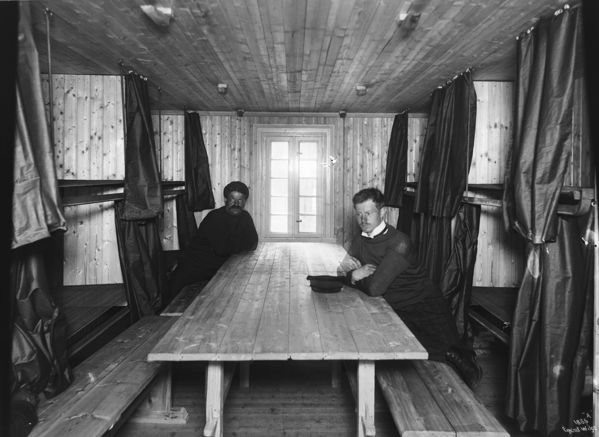 To menn sitter ved et bord i en sovesal ved steinbrudd i Heestrand, Sverige, 28.6.1902.