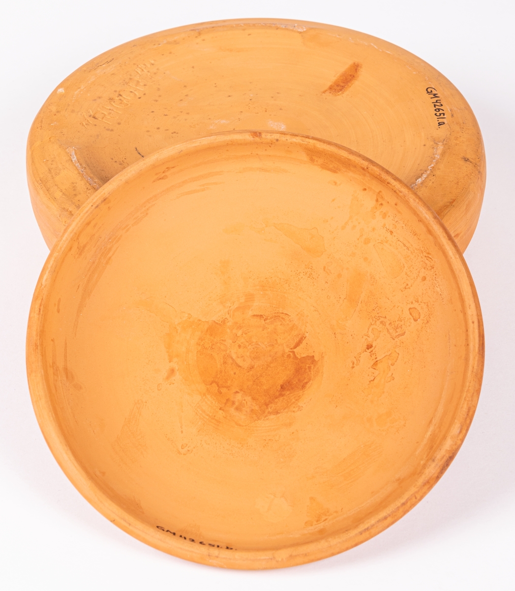 Smörkylare av oglaserad keramik, rund med lock. Kylaren saknar invändig skål för smöret, ofta i porslin eller glas. Smöret skulle ligga i porslinsskålen och runt den hälldes kallt vatten eller krossad is. Rigor är modellnamnet på kylaren.