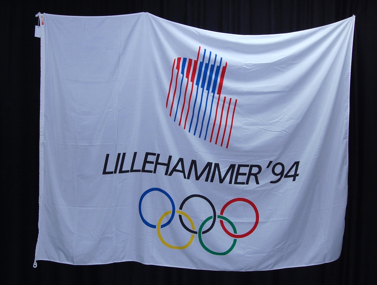 Hvitt flagg med rød og blå logo for de olympiske vinterleker på Lillehammer i 1994. De olympiske ringer i farger er også på flagget.
