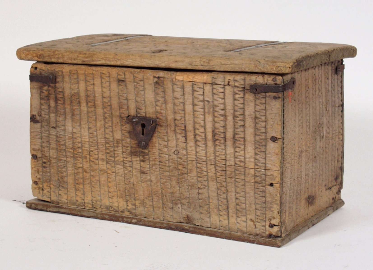Kista er laget av furu og har lås og beslag av jern. Dekorert med karveskurd på lokket.