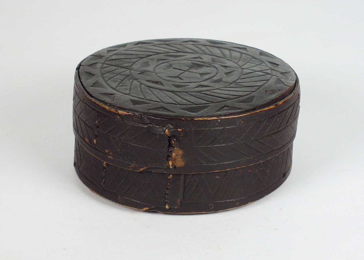 Ei svart øskje i bjørk og furubunn. På lokket og korpus har den utskåret kors og skrålinjer i kilesnitt. Den er blitt sveipet med einer.