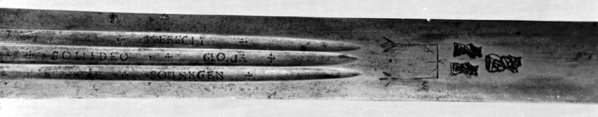 Skarprettersverd.  Pæreformet knapp med fasettetert dekor.
Tregrep viklet med rokkeskinn. 
Rette åttekantede parérstenger som ender i to dråper med kantet dekor. Rett tveegget klinge med ovalt tverrsnitt  og tre korte blodrender på hver side. Innslått tre smedstempler med kronede hoder.  På den ene siden er det gravert inn et hjul og på den andre siden en galge. Begge inngraveringer er innlagt med kobber.

