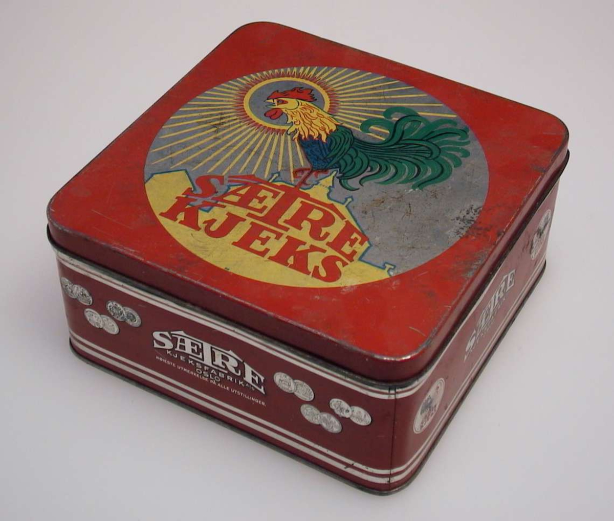 Firkantet kakeboks med hanemotiv på lokket.