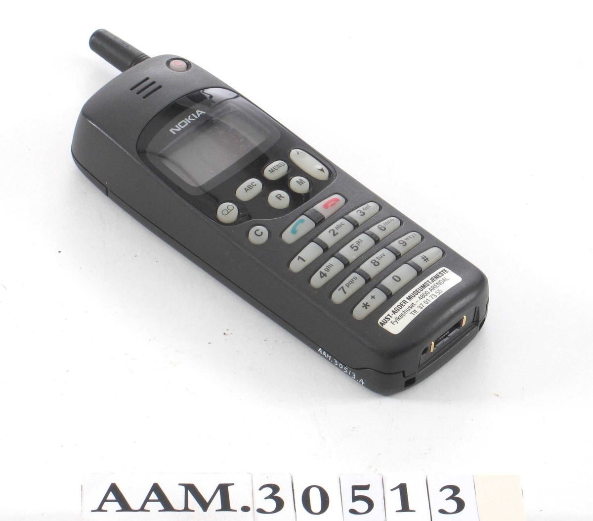 Rektangulær, med liten antenne. 
Telefonen (AAM.30513.A) ligger i eske (AAM.30513.B), sammen med tilhørende bruksanvisninger og brev vedrørende abonnement. Den første mobiltelefonen til Aust-Agder museumstjeneste.