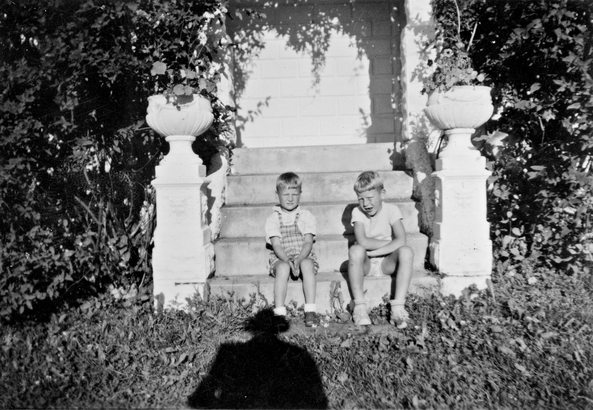 Steinar og Egil sitter på trapp ved veranda.