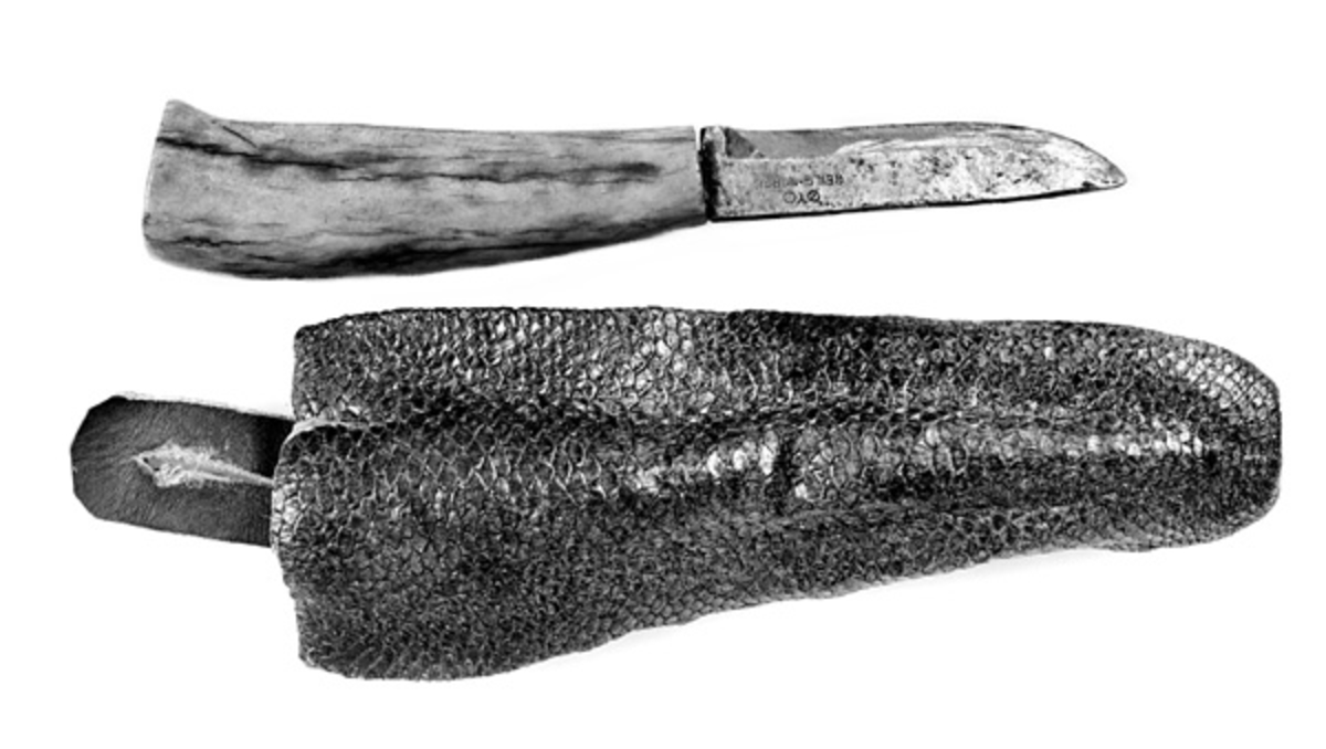 Kniven har skaft av elghorn. Slira er skinnet av en beverhale. Giveren, som er en kjent bever- og revejeger, laget kniven omkring 1960. 