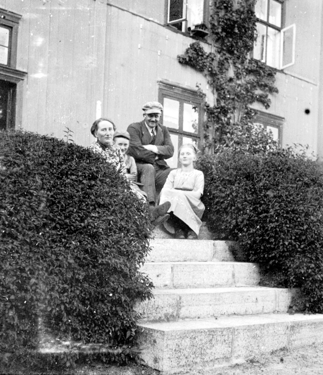 Familie foran hovedbygning med terasse på Nederkvern gård, Brumunddal. Fra venstre er Marta Antonie Bjerke f.1872, Thore Otto Grüner Bjerke f.1903, Thore Kristian Bjerke f.1872, Ingeborg Marie Bjerke f.1902.