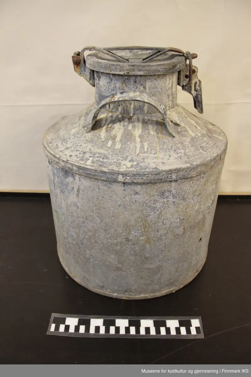 Stort spann (ant 30 liter) med håndtak på to sider av halsen og kraftig henglset lokk med gummipakning, Antatt benyttet  til oppbevaring av kjemikalier, siste bruk ser ut til å ha vært som malingspann.
