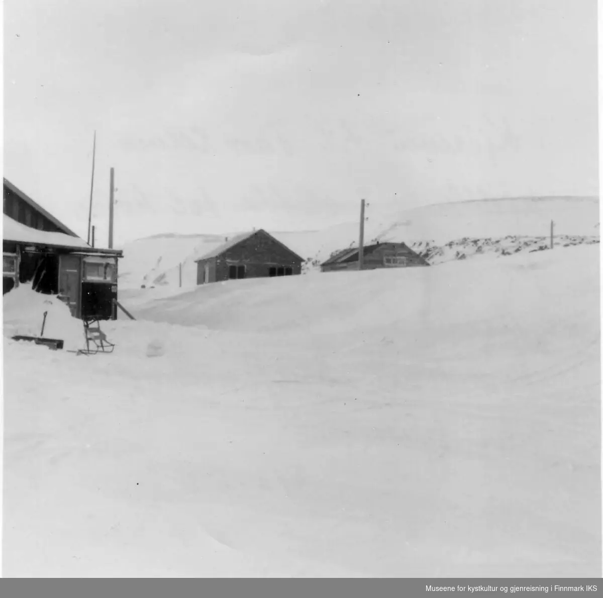 Snøfonn dekker kjøreveien til Thor Ulves fiskehjeller. Hjellene lå på sletta til høyre for Iversens eiendom. Fotoet er tatt fra den gamle kirketomta. 1952