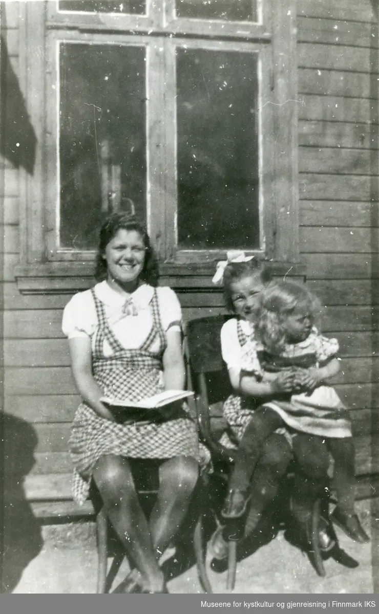 Tre jenter sitter på stoler ute ved en husvegg, antagelig 1930-tallet i Finnkongkeila.